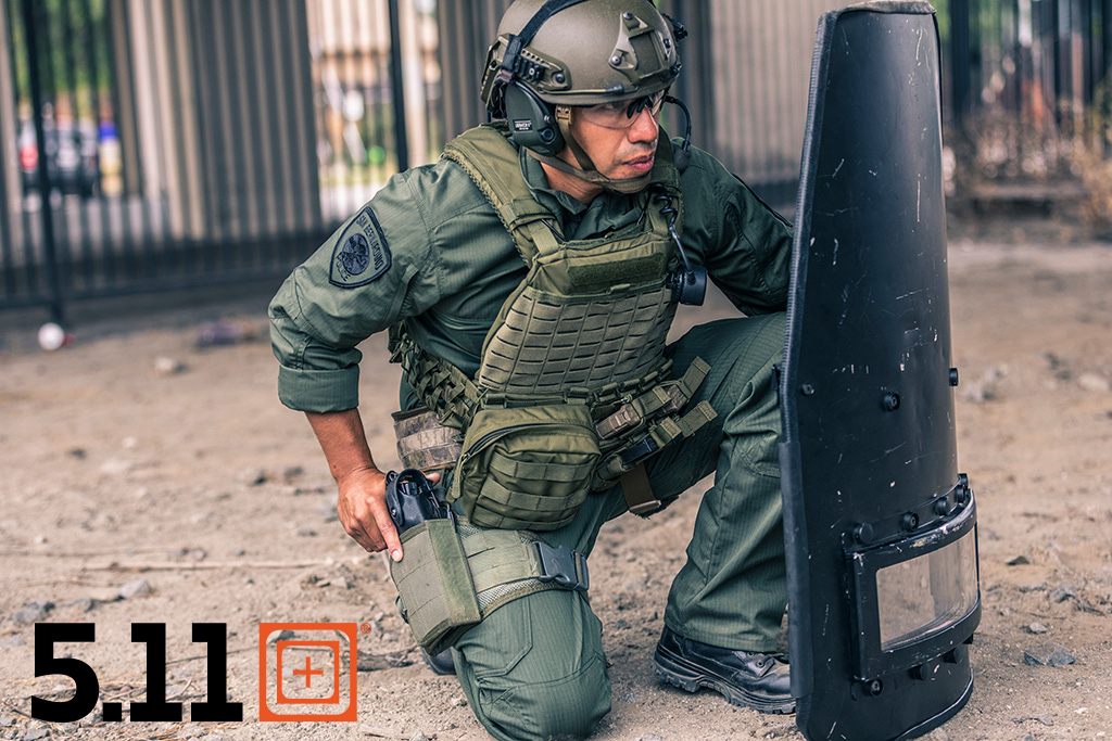 Tactical vest with riot shield and load out gear
